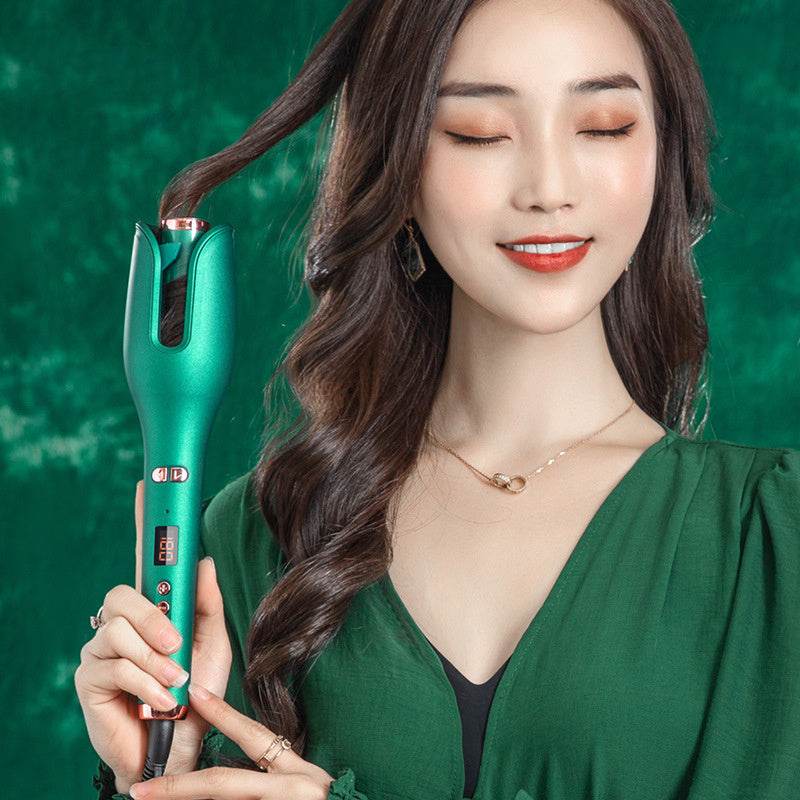 Woman using green automatic hair curler styling long wavy hair